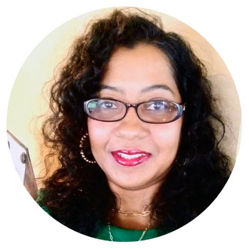 Smiling woman with curly hair and glasses.
