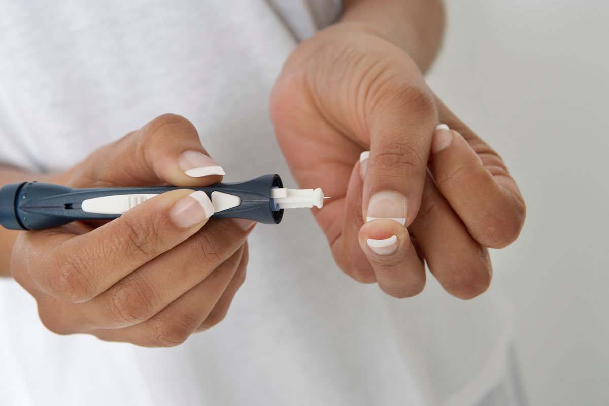 Woman injecting insulin using syringe, close-up of hands