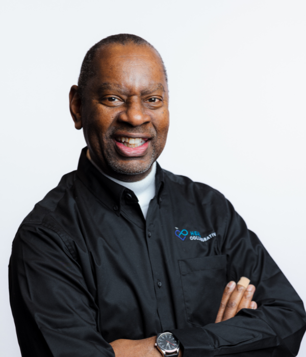 Smiling professional man in black chef jacket with arms crossed.